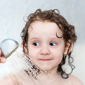little girl in the bathroom holding a shower