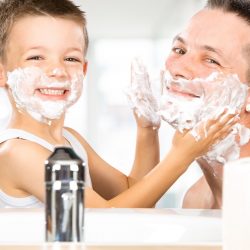 happy child have fun with dad with shaving foam in the bathroom